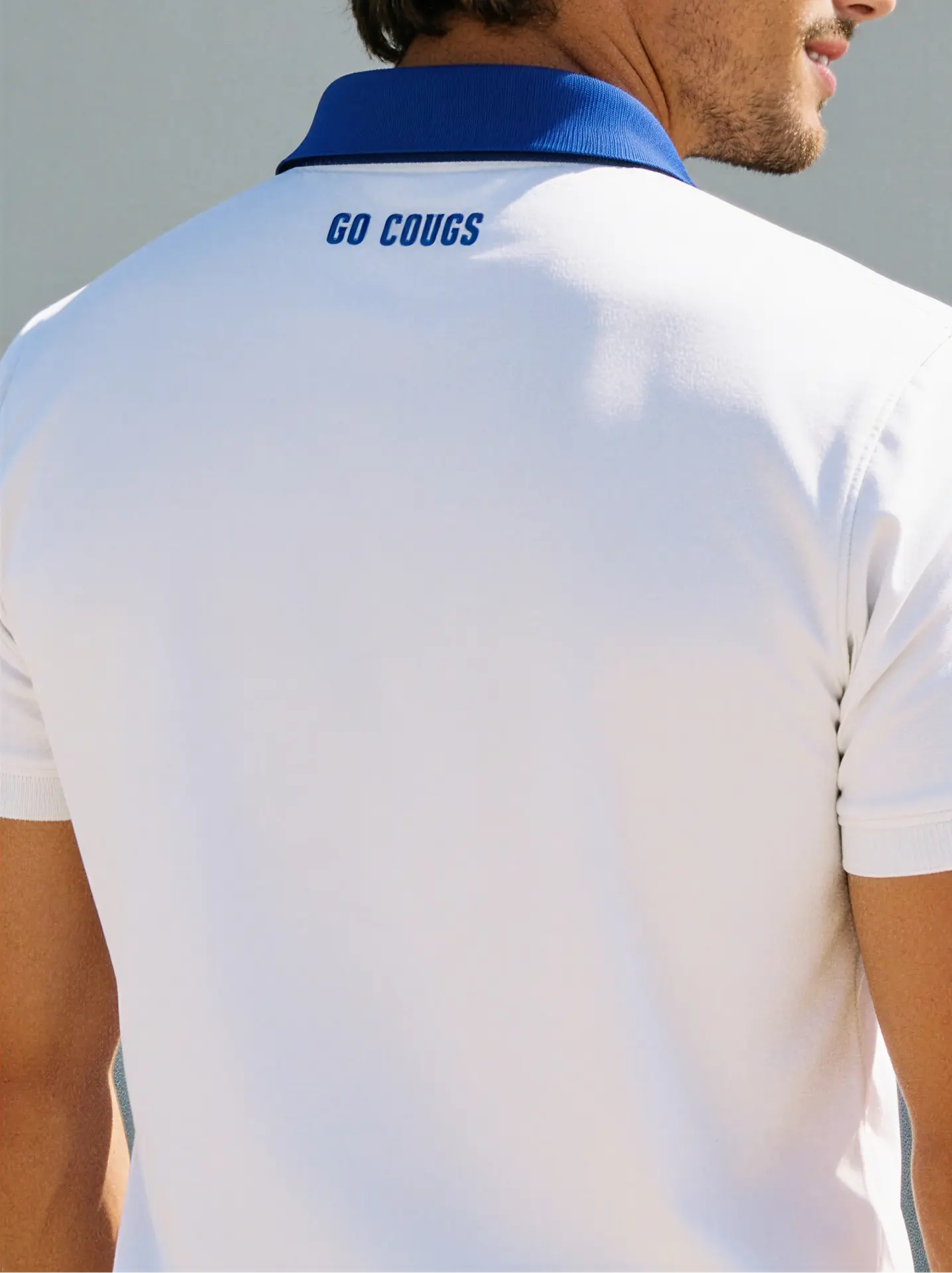 Back of a white polo with a small embroidered school slogan